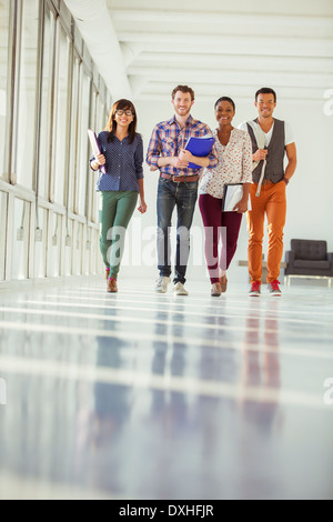 Portrait of creative business people walking in sunny corridor Stock Photo