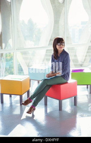 Creative businesswoman waiting on colorful stool Stock Photo