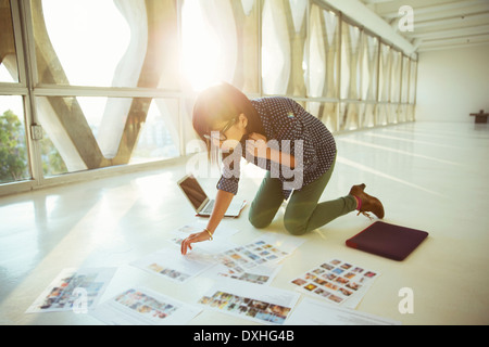 Creative businesswoman reviewing photography proofs on office floor Stock Photo