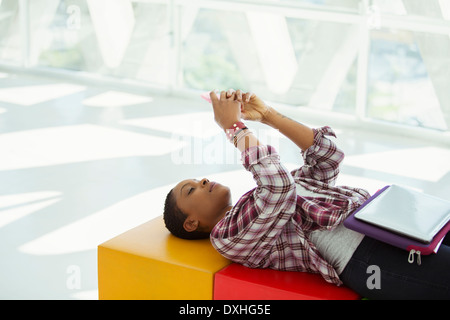 Casual businesswoman laying on bench and text messaging with cell phone Stock Photo