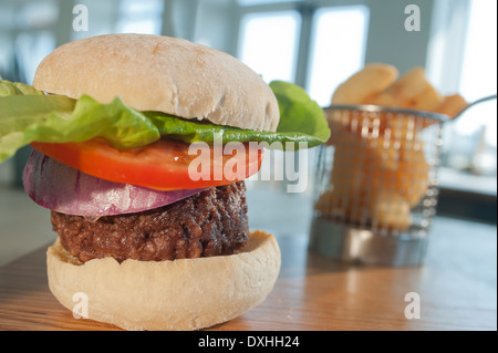 Burger in bun with salad extras (Onion, tomato and lettuce) with a side order of French fried potatoes or chips. Stock Photo