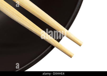 Chopsticks on a black bowl with white background Stock Photo