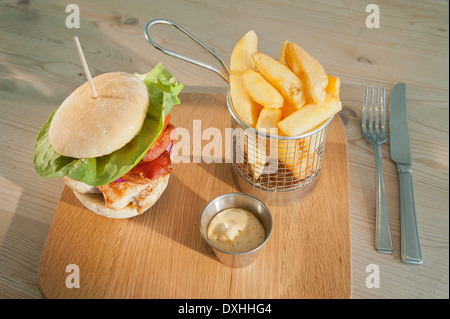 Chicken and bacon burger with side orders of mayonnaise and French fried or chipped potatoes. (Fries or Chips)