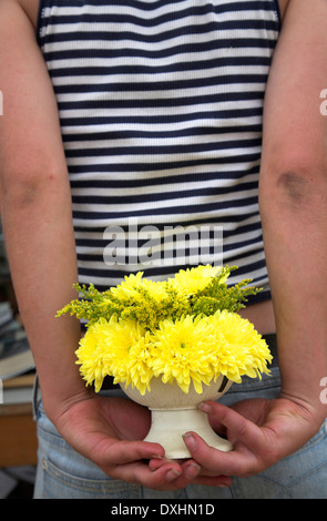 Model Released image of Yellow flowers held behind a girl´s back about to be given as a surprise present Stock Photo