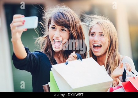 Beautiful girls with shopping bags taking a 'selfie' with their cell phone Stock Photo