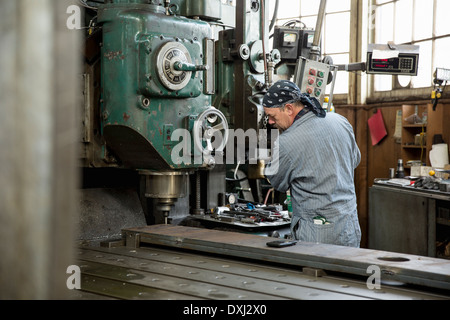 Man using machinery in metal shop Stock Photo