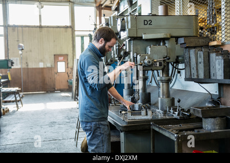 Caucasian man using drilling machine in metal shop Stock Photo