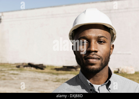 Close up portrait of Black man wearing hard-hat at construction site Stock Photo