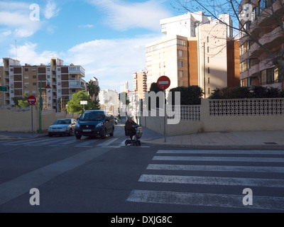 Person on a mobility scooter crossing a road in Benidorm, Spain. Stock Photo