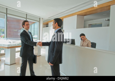 two businessmen shaking hands in office reception Stock Photo