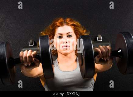 Caucasian woman doing chest presses with dumbbells in gym Stock Photo