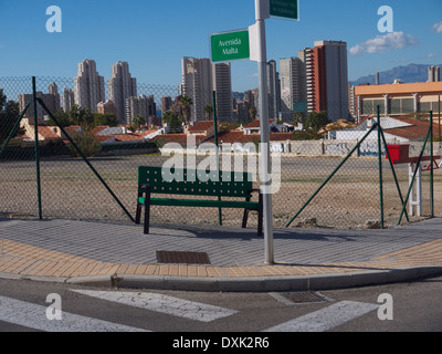 Bench on a street corner sloping down hill Stock Photo