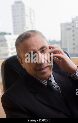 Portrait of Hispanic businessman talking on cell phone in office Stock Photo