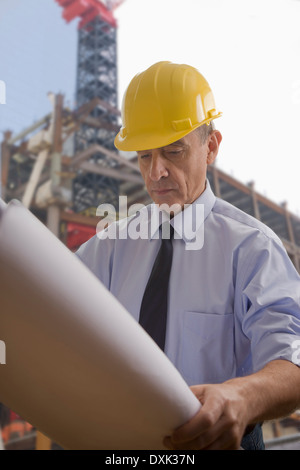 Hispanic architect reviewing blueprints at construction site Stock Photo