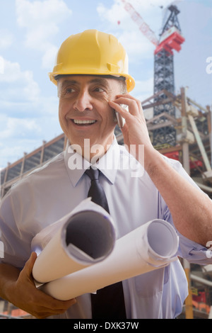 Hispanic architect talking on cell phone at construction site Stock Photo