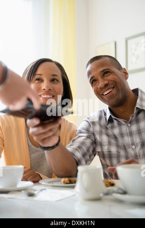 Couple receiving bill from waitress in restaurant Stock Photo