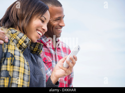 Happy couple using cell phone outdoors Stock Photo