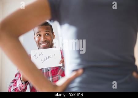 Man showing 'I'm Sorry' sign to angry girlfriend Stock Photo