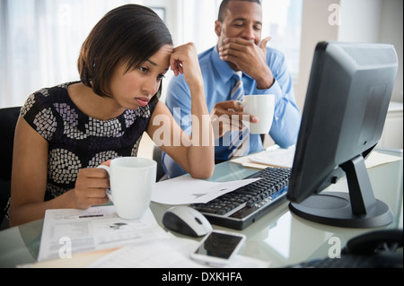 Exhausted business people with coffee working at computer Stock Photo