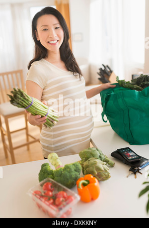 Portrait of pregnant Japanese woman unloading groceries Stock Photo