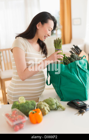 Pregnant Japanese woman unloading groceries Stock Photo