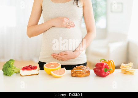 Health and unhealthy foods in front of pregnant Japanese woman Stock Photo