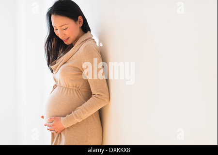 Pregnant Japanese woman holding stomach Stock Photo