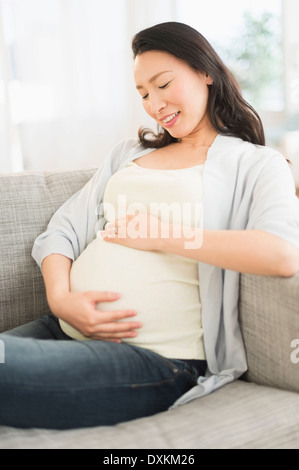 Pregnant Japanese woman holding stomach Stock Photo