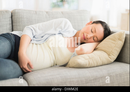 Pregnant Japanese woman napping on sofa Stock Photo