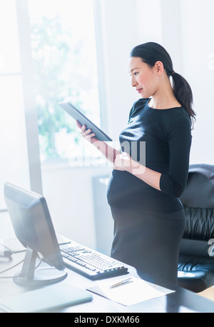 Pregnant Japanese businesswoman using digital tablet Stock Photo