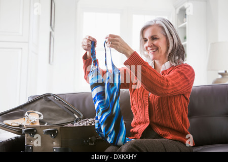 Caucasian woman packing bathing suit in suitcase Stock Photo