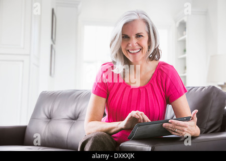 Portrait of smiling Caucasian woman using digital tablet on sofa Stock Photo