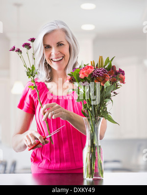 Portrait of smiling Caucasian woman arranging flowers Stock Photo