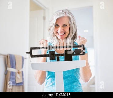 Excited Caucasian woman cheering on weight scale Stock Photo