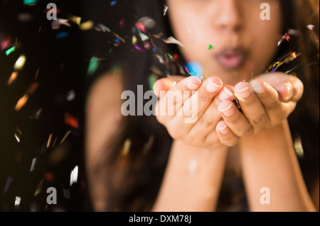 Close up of Asian woman blowing confetti from hands Stock Photo