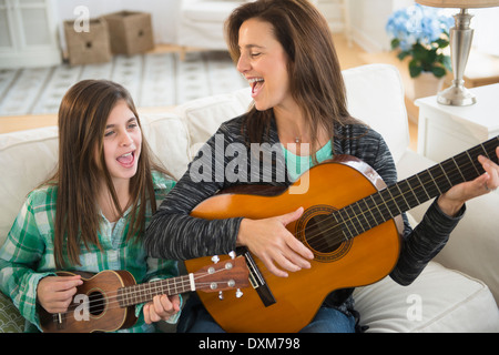 Caucasian mother and daughter singing with guitar and ukulele Stock Photo