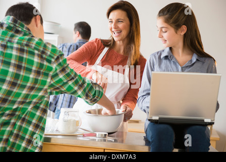 Caucasian family baking and using laptop in kitchen Stock Photo