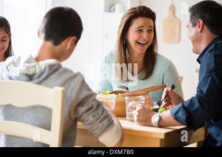 Caucasian family laughing and eating at table Stock Photo