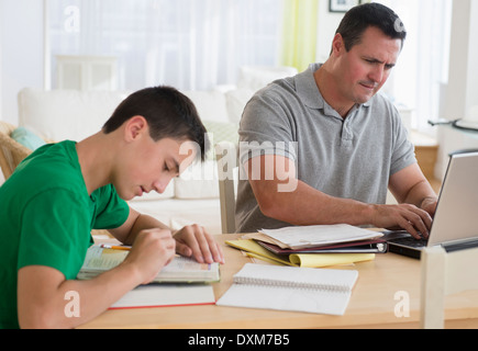 Caucasian father using laptop near studying son Stock Photo