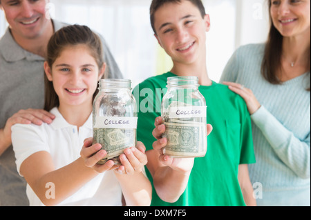 Proud Caucasian parents watching children with college savings jars Stock Photo