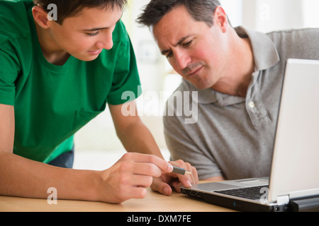 Caucasian son showing father how to use USB stick in laptop Stock Photo