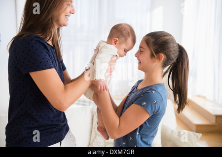 Caucasian mother handing baby girl to daughter Stock Photo