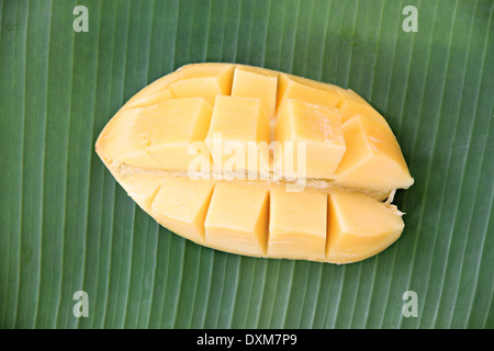 Ripe mango with slices on banana leaves of background. Stock Photo