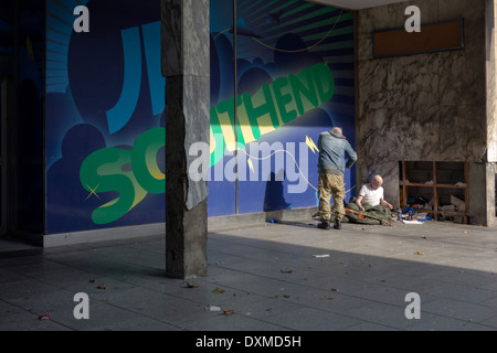 Two homeless people in a quiet corner close to a high street. Stock Photo