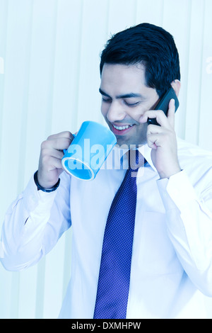 1 Indian Businessman Drinking Tea and Talking with Mobile Stock Photo