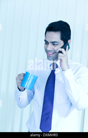 1 Indian Businessman Drinking Tea and Talking with Mobile Stock Photo
