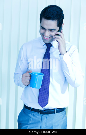 1 Indian Businessman Drinking Tea and Talking with Mobile Stock Photo
