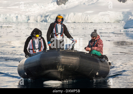 Crew members of an expedition cruise to Antarctica in a Zodiak in Fournier Bay in the Gerlache Strait on the Antarctic Peninsular, dressed up as penguins. The Antarctic Peninsular is one of the most rapidly warming areas on the planet. Stock Photo