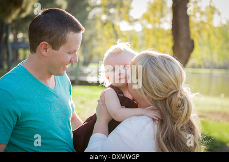 Cute Young Baby Boy Being Hugged By His Parents Outside at the Park. Stock Photo