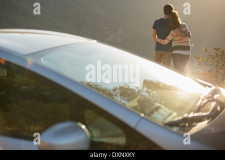 Couple hugging outside car at roadside Stock Photo